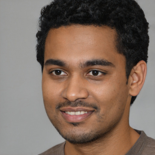 Joyful black young-adult male with short  black hair and brown eyes
