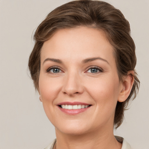 Joyful white young-adult female with medium  brown hair and grey eyes