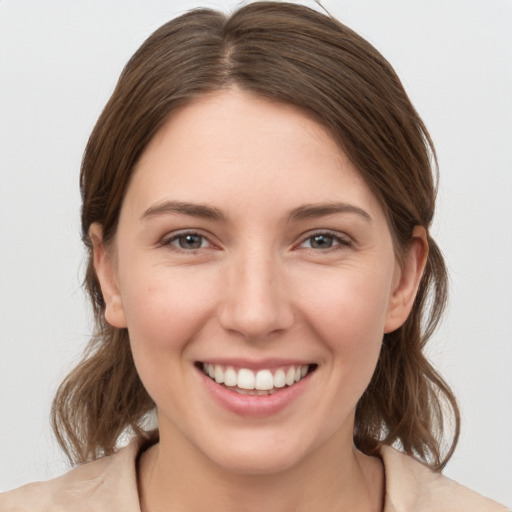 Joyful white young-adult female with medium  brown hair and grey eyes