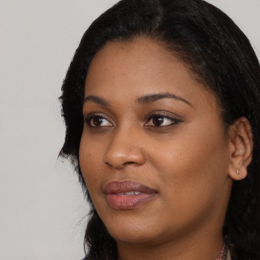 Joyful black young-adult female with long  black hair and brown eyes