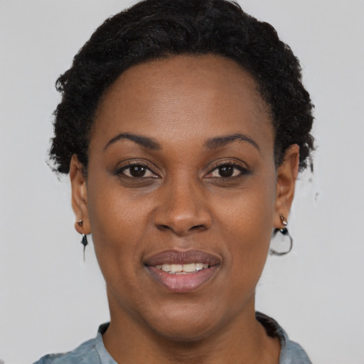 Joyful black adult female with short  black hair and brown eyes