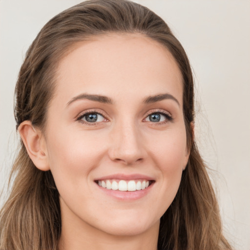 Joyful white young-adult female with long  brown hair and blue eyes