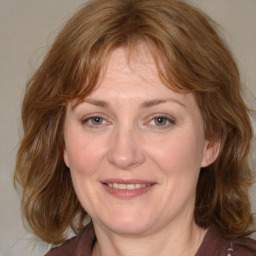 Joyful white adult female with medium  brown hair and blue eyes