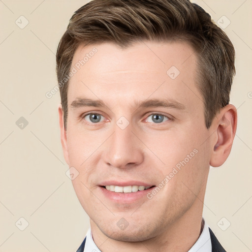 Joyful white young-adult male with short  brown hair and grey eyes