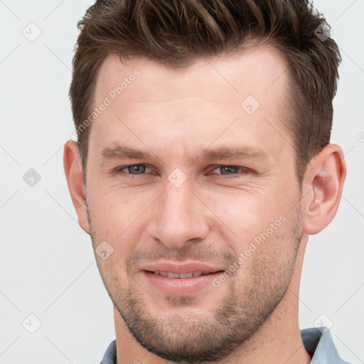 Joyful white young-adult male with short  brown hair and grey eyes