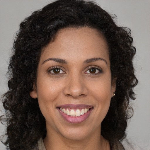Joyful black young-adult female with long  brown hair and brown eyes