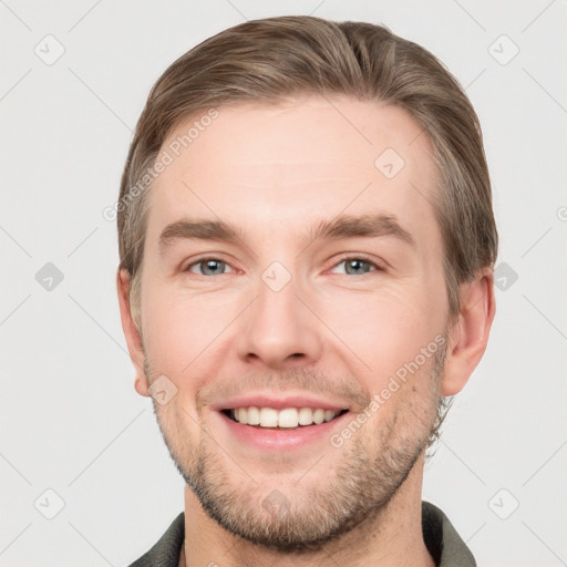 Joyful white young-adult male with short  brown hair and grey eyes