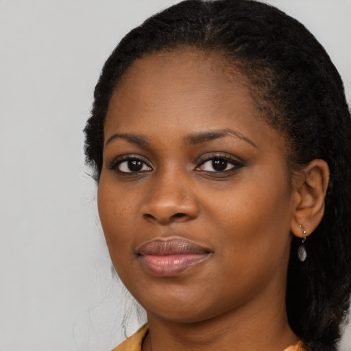 Joyful black young-adult female with long  black hair and brown eyes