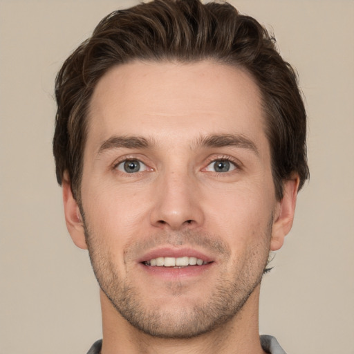 Joyful white young-adult male with short  brown hair and grey eyes