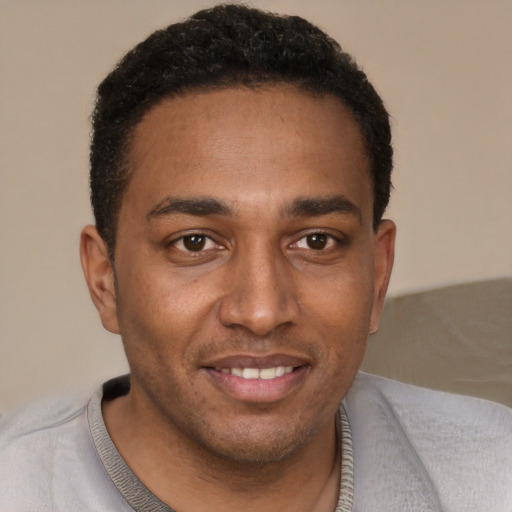 Joyful black young-adult male with short  black hair and brown eyes