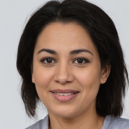 Joyful latino young-adult female with medium  brown hair and brown eyes