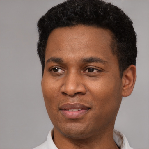 Joyful black young-adult male with short  black hair and brown eyes