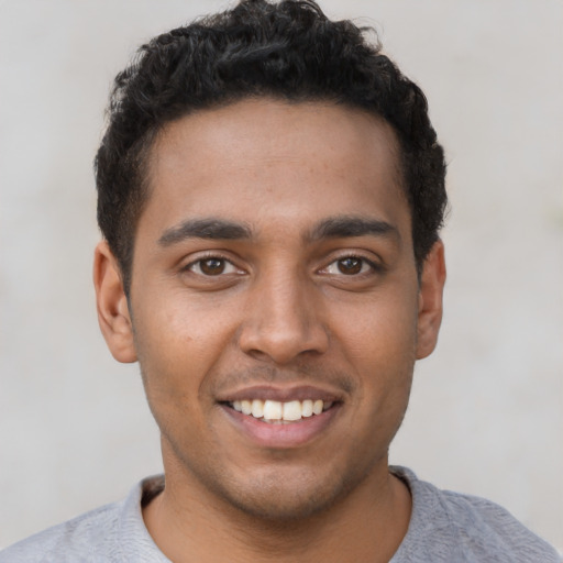 Joyful black young-adult male with short  brown hair and brown eyes