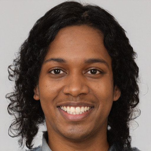 Joyful black young-adult female with long  black hair and brown eyes