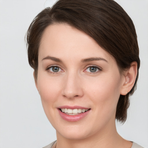 Joyful white young-adult female with medium  brown hair and grey eyes