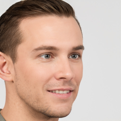 Joyful white young-adult male with short  brown hair and grey eyes