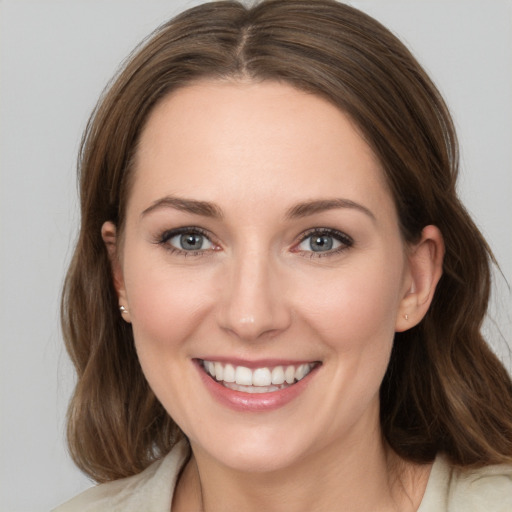 Joyful white young-adult female with medium  brown hair and grey eyes