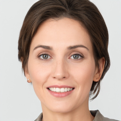 Joyful white young-adult female with medium  brown hair and grey eyes