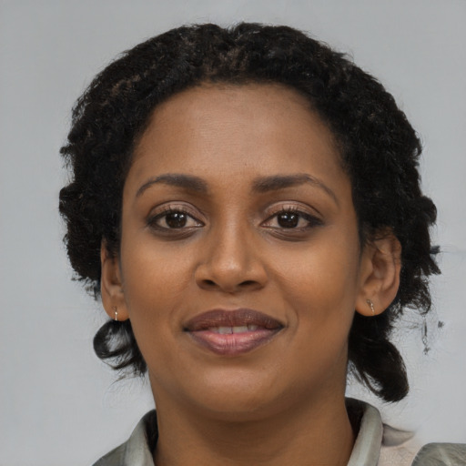 Joyful black young-adult female with medium  black hair and brown eyes