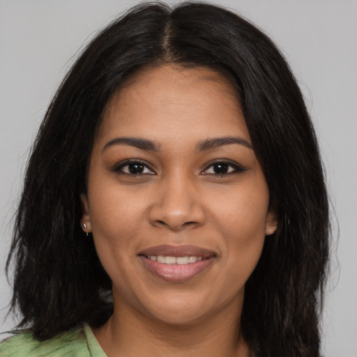 Joyful black young-adult female with long  brown hair and brown eyes