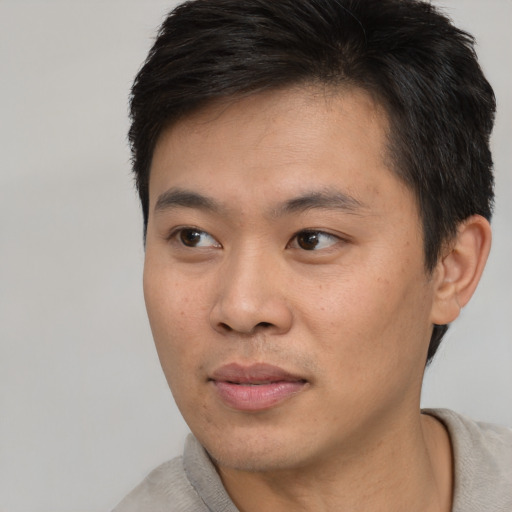 Joyful asian young-adult male with short  black hair and brown eyes