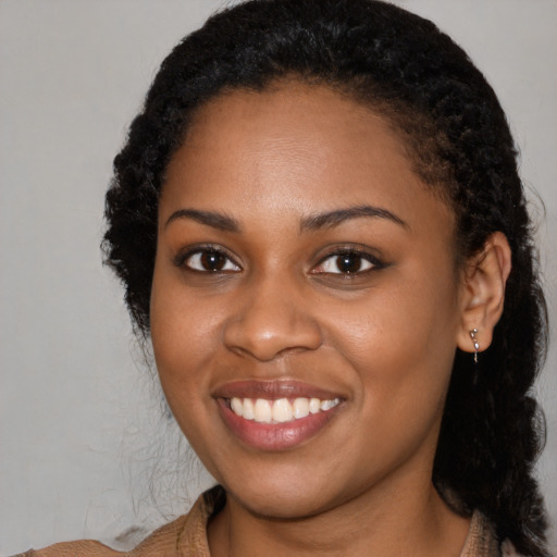 Joyful black young-adult female with long  black hair and brown eyes