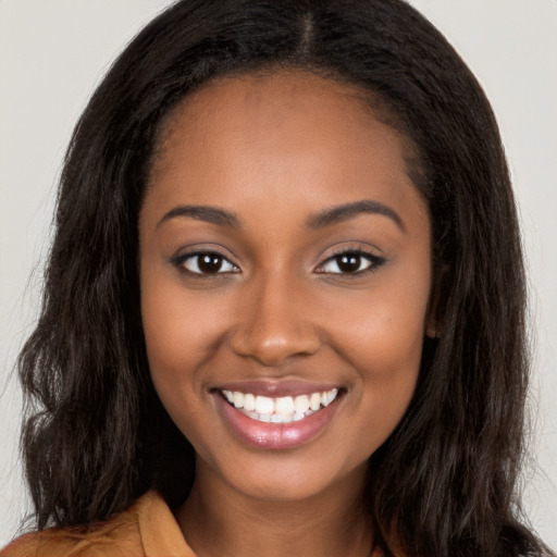 Joyful black young-adult female with long  brown hair and brown eyes