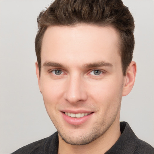 Joyful white young-adult male with short  brown hair and grey eyes