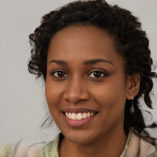 Joyful black young-adult female with long  brown hair and brown eyes