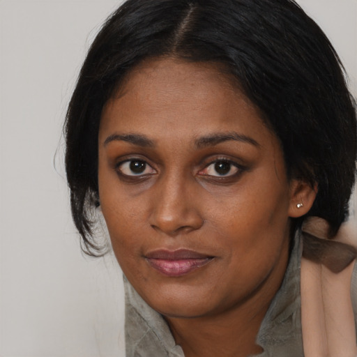 Joyful black young-adult female with long  brown hair and brown eyes