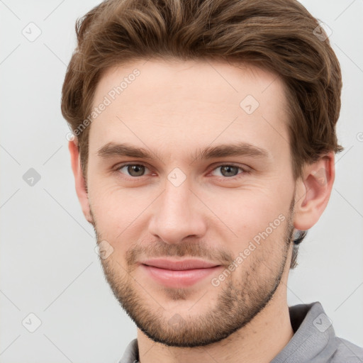 Joyful white young-adult male with short  brown hair and grey eyes