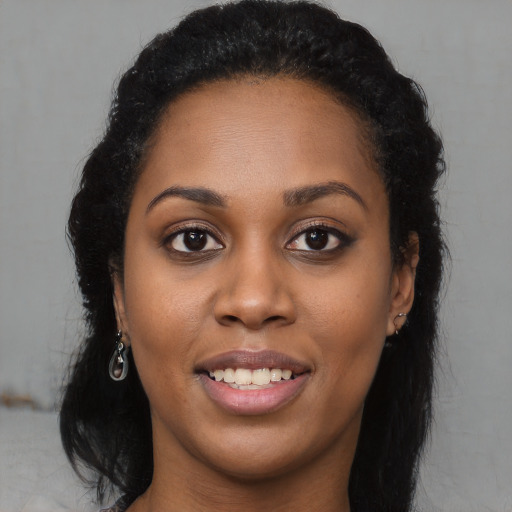 Joyful black young-adult female with long  brown hair and brown eyes