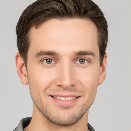 Joyful white young-adult male with short  brown hair and grey eyes