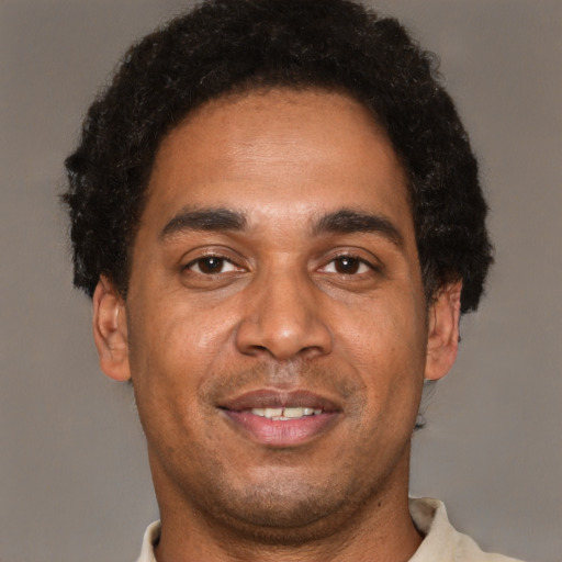 Joyful black young-adult male with short  brown hair and brown eyes