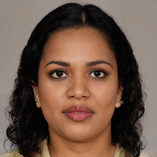 Joyful black young-adult female with long  brown hair and brown eyes