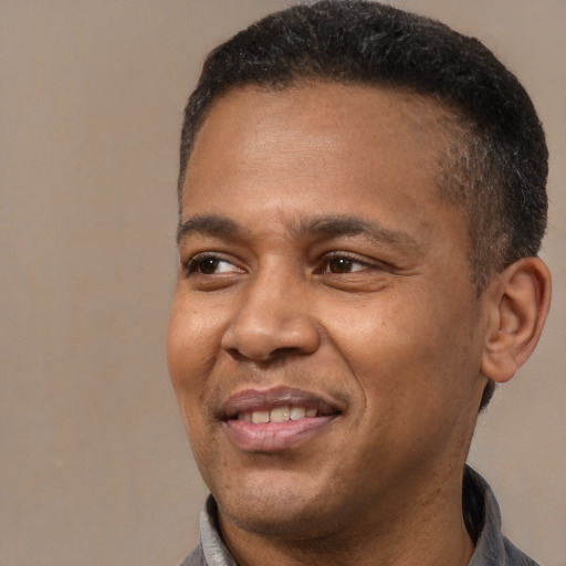 Joyful black adult male with short  brown hair and brown eyes