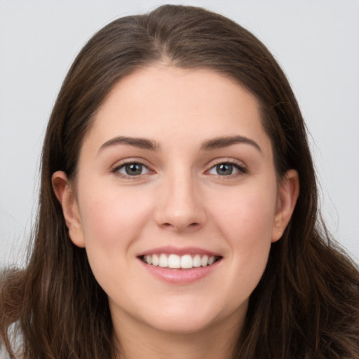 Joyful white young-adult female with long  brown hair and brown eyes