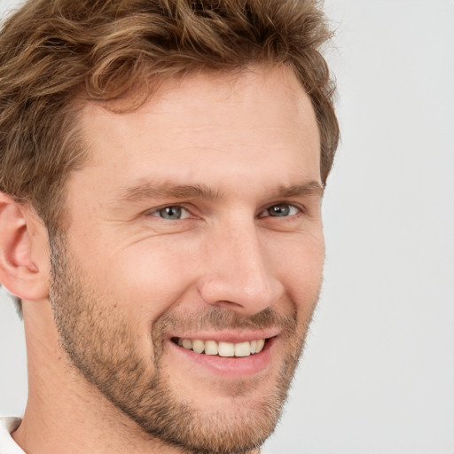 Joyful white young-adult male with short  brown hair and grey eyes