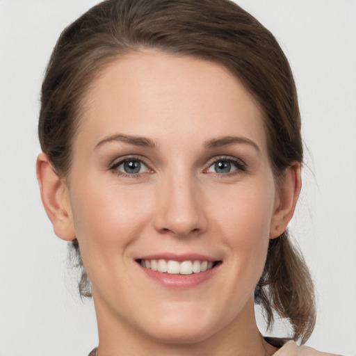 Joyful white young-adult female with medium  brown hair and grey eyes