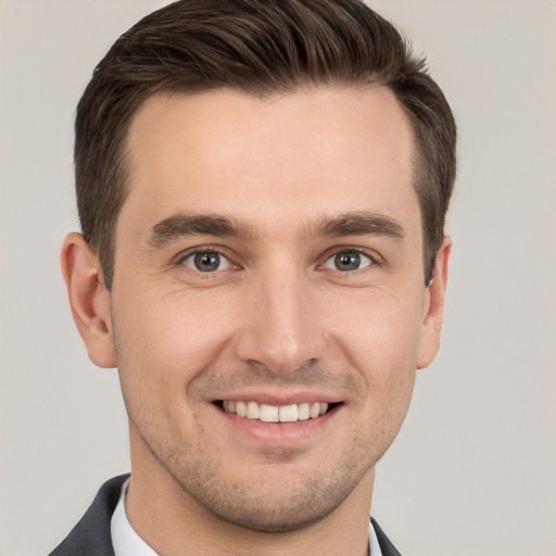 Joyful white young-adult male with short  brown hair and grey eyes