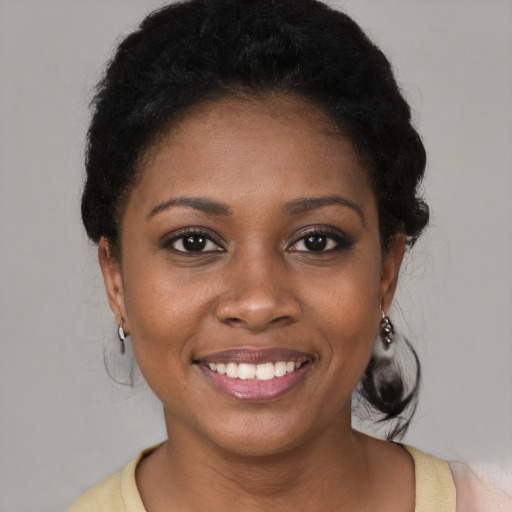 Joyful black young-adult female with short  black hair and brown eyes