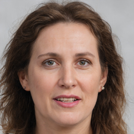 Joyful white adult female with long  brown hair and grey eyes