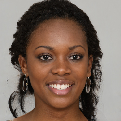 Joyful black young-adult female with long  brown hair and brown eyes