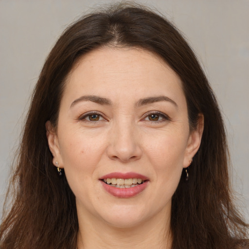 Joyful white adult female with long  brown hair and brown eyes