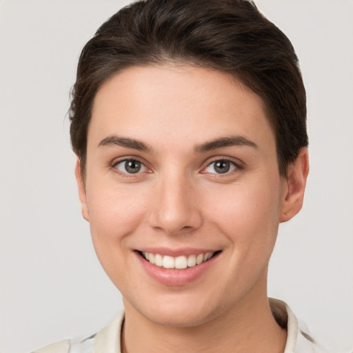 Joyful white young-adult female with short  brown hair and grey eyes