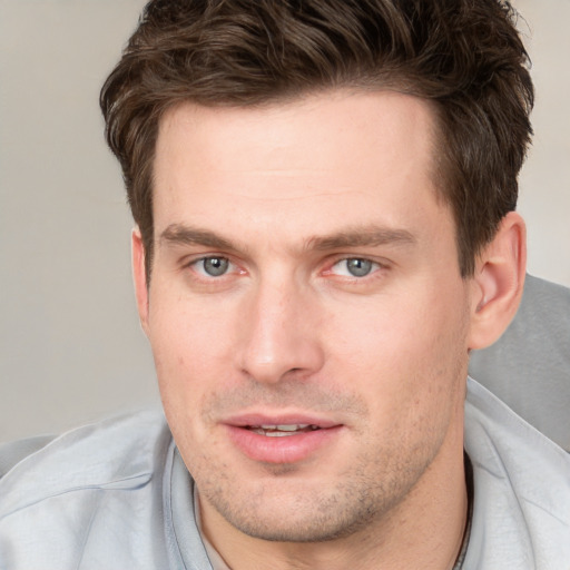 Joyful white young-adult male with short  brown hair and grey eyes