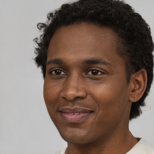 Joyful black young-adult male with short  brown hair and brown eyes