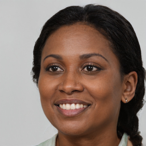 Joyful black young-adult female with long  black hair and brown eyes