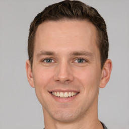 Joyful white young-adult male with short  brown hair and grey eyes