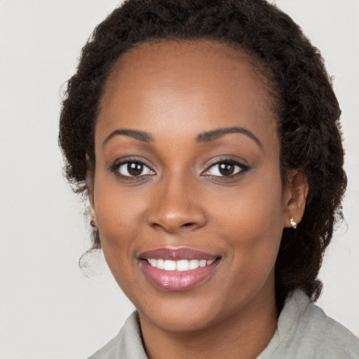 Joyful black young-adult female with medium  brown hair and brown eyes